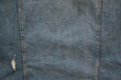 one small ragged hole and two vertical seams on old blue denim for background or wallpaper
