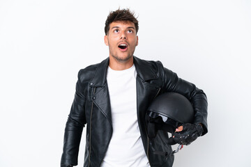 Wall Mural - Young caucasian man with a motorcycle helmet isolated on white background looking up and with surprised expression