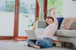 © interstid - Asian woman stretching her arms for relax after working at home via laptop in living room at home