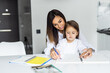 © F8  \ Suport Ukraine - Loving young mother and little preschooler daughter sit at table drawing on paper together. Caring mum or nanny playing with small girl child, paint pictures in notebook, early development concept