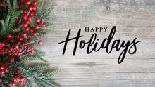 Happy Holidays Script Text With Holiday Evergreen Branches And Red Berries On Side Over Rustic Wood Background