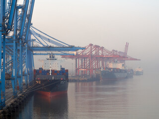 India, Mumbai Port Trust - 25 January, 2017: View to moored container vessels with port cranes during the morning fog.