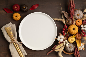 Rustic menu mockup with plate and autumn table decoration.  Floral interior decor for fall holidays with handmade pumpkins. Holiday dinner concept. Flatlay, top view.