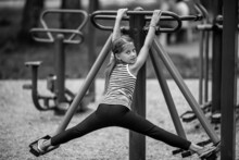 Little Girl On A Trainer-machine On The Playground. Black And White Photo.