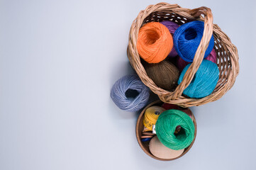 Poster - Pile of colorful textile balls of wool in a wicker basket on gray background with a copy space