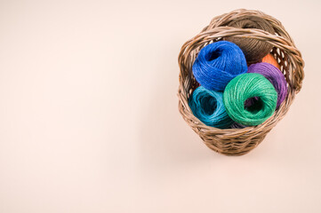 Canvas Print - Pile of colorful textile balls of wool in a wicker basket on brown background with a copy space