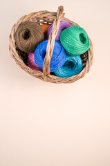 Poster - Pile of colorful textile balls of wool in a wicker basket on brown background with a copy space