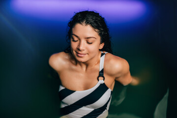 Wall Mural - Beautiful woman floating in tank filled with dense salt water used in meditation, therapy, and alternative medicine. .