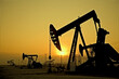 © Tetra Images - Silhouette of pump jacks in oil field at sunset