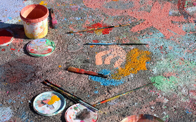 Jars, lids and dirty used brushes on painted asphalt in natural light, used to create street art or graffiti. Asphalt, painted with adult and children's drawings. High quality photo