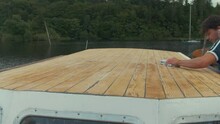 Wiping Down Sanded Roof Of Wooden Boat With Cloth And Paint Thinners