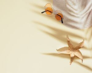 Canvas Print - Summer beach rest concept background with hat, orange sunglasses, starfish on sandy color paper with palm shadows