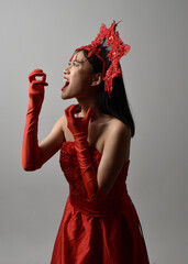 Wall Mural - portrait of beautiful young asian woman wearing red corset, posing in gothic horror style with creative hand gestures isolated against  studio background.