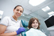 © mad_production - Beautiful female dentist and her young patient smiling to the camera after dental checkup