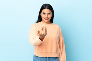 Wall Mural - Young latin woman woman isolated on blue background inviting to come with hand. Happy that you came