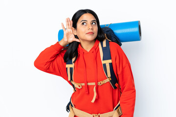 Wall Mural - Young Colombian mountaineer girl with a big backpack isolated on white background listening something