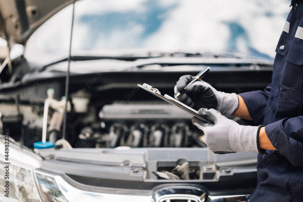 Car service, repair, maintenance concept,auto mechanic man or Smith writing to the clipboard at workshop, technician doing the checklist for repair machine a car in the garage,banner.