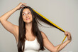 © vladimirfloyd - a young happy woman shows the length of her hair with a measuring tape