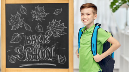 Poster - education, learning and people concept - happy smiling student boy with bag over chalkboard with back to school lettering on background