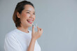 close up young asian woman smiling with hand holding dental aligner retainer (invisible) on gray background of dental clinic for beautiful teeth treatment course concept