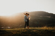© Halfpoint - Young couple on a walk in nature at sunset in countryside, hugging.