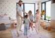 © Halfpoint - Father with three daughters indoors at home, playing on floor and jumping.
