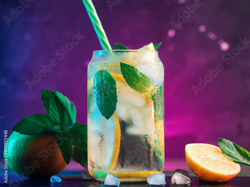 Refreshing cold tonic with lemon and mint, ice lemonade in a glass, neon stylish background