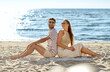 © Syda Productions - leisure, relationships and people concept - happy couple in sunglasses sitting back to back on summer beach