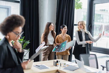 blurred african american businesswoman near multicultural managers working with analytics on background