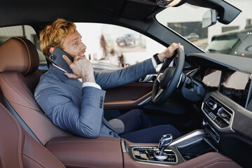 Canvas Print - Side view smiling man driver male cabdriver wearing classic grey suit drive car hold wheel talk by mobile cell phone in traffic jam test auto want buy new automobile vehicle Sale transport concept