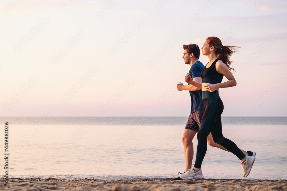 Full body profile couple young two friends strong sporty sportswoman sportsman woman man 20s in sport clothes warm up training run on sand sea ocean beach outdoor jog on seaside in summer day morning. - obrazy, fototapety, plakaty 