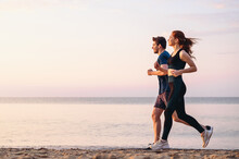 Full Body Profile Couple Young Two Friends Strong Sporty Sportswoman Sportsman Woman Man 20s In Sport Clothes Warm Up Training Run On Sand Sea Ocean Beach Outdoor Jog On Seaside In Summer Day Morning.