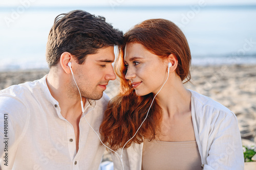 Close up young couple two family man woman in white clothes hug sitting sand listen to music headphones rest relax together at sunrise over sea beach ocean outsideseaside in summer day sunset evening