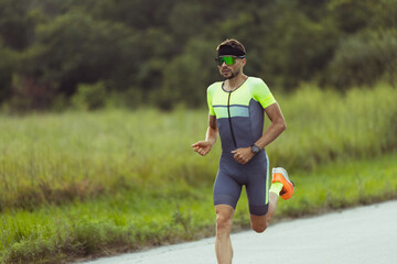 Wall Mural - Young professional male triathlete, runner in motion on open road. Concept of sport, lifestyle, activity