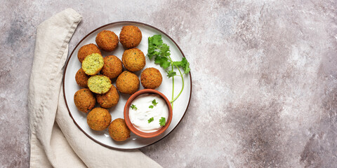 Vegetarian falafel balls with sauce on a grunge background. Top view, flat lay, copy space. Middle Eastern traditional dish. Wide composition