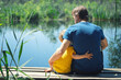 © Gargonia - Happy father and son hugging sitting on wooden pier near lake on sunny summer day. Dad and child boy spend time together on wharf. Father's day concept.