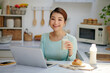 © makistock - Young attractive asian businesswoman drinking milk while sitting at office desk