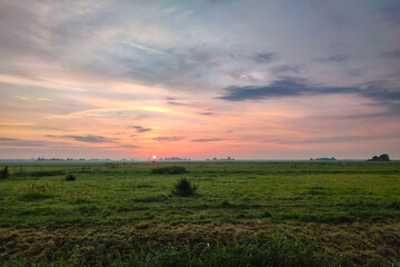 Wall Mural - the sun sets over the wide open dutch landscape, casting beautiful colors over the green meadows