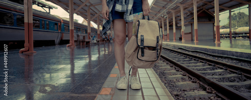 Banner web page or cover template. Travel concept. Woman traveler tourist waiting for the train with a backpack, traveling map nearing railway at the train station.