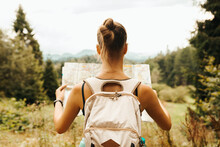 Hiking Young Woman Traveler With Backpack Checks Map To Find Directions In Wilderness Area, Real Explorer. Travel Concept
