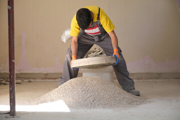 Young builder sieving sand at a construction site.