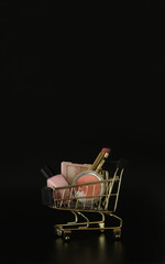 Wall Mural - Shopping trolley full of make up and cosmetic goods on black background. Black friday concept. Sale and discount. Goods for women. Beauty background, free space for text, copy space