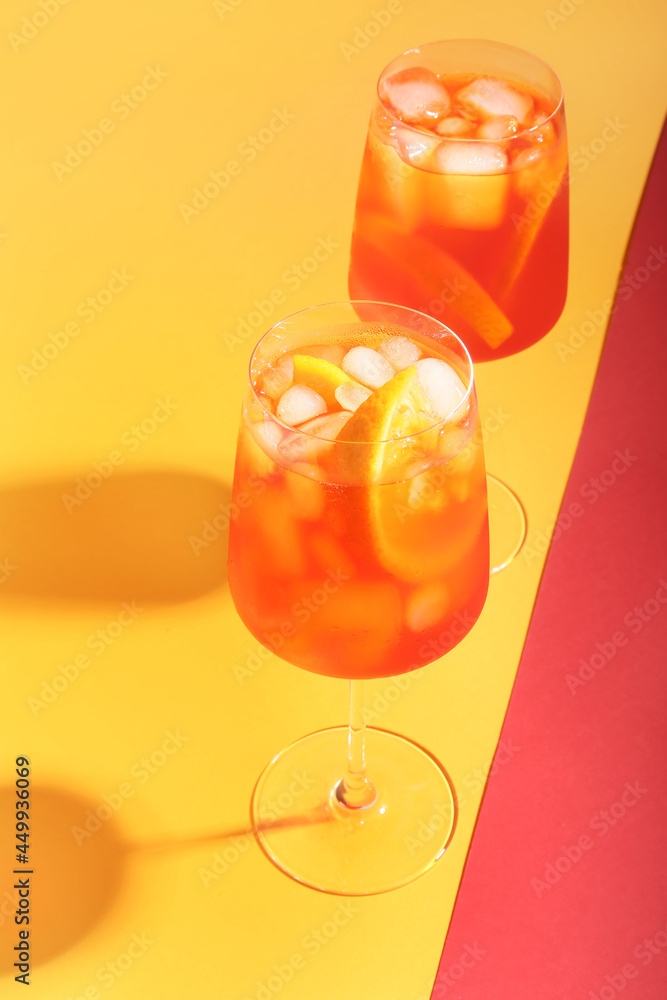 Glasses of Aperol spritz cocktail on color background