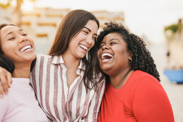 Wall Mural - Multiracial girls laughing together in the city while hugging each other - Young latin women outdoor