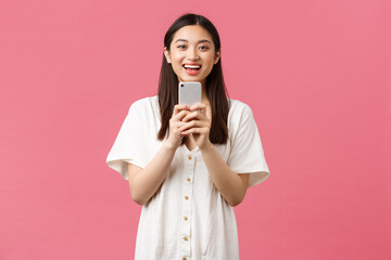 Beauty, people emotions and technology concept. Smiling happy asian female blogger, stylish girl taking photo on smartphone, looking upbeat as photographing, taking picture with mobile phone