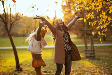 mother and child outdoors in city park in autumn rejoicing