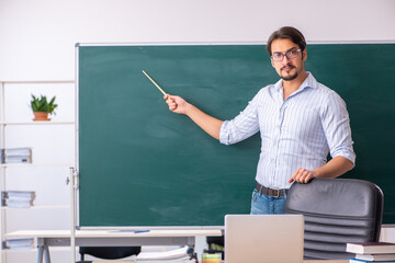 Wall Mural - Young male teacher in front of blackboard