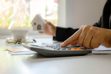 Wall Mural - Close-up of male businessman's hands using a calculator and taking notes accounting report concept of costing and saving money