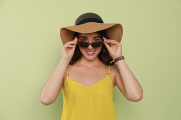 Sticker - Beautiful young woman with straw hat and stylish sunglasses on light green background