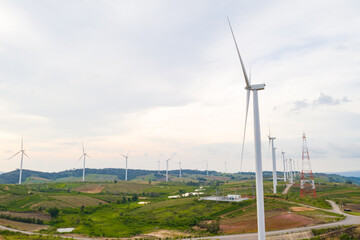 Aerial view, windmills rotating by the force of the wind and generating clean renewable energy for sustainable development in a green ecologic way on cloudy sky at highland. Drone shot